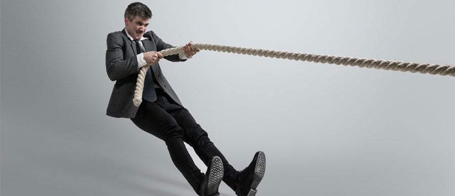 Overcoming-Challenges-man-office-clothes-training-with-ropes-grey-background