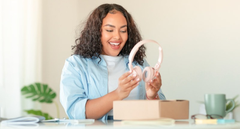 excited-african-american-woman-unpacking-box-with-headphones-home (1)