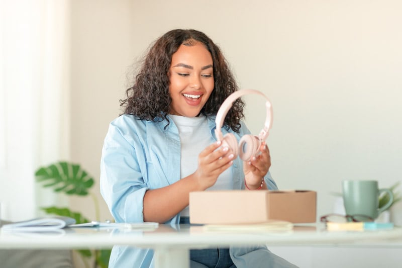 excited-african-american-woman-unpacking-box-with-headphones-home (1)